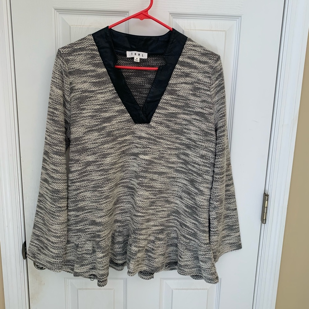Long sleeve top with faux leather and ruffle hem.